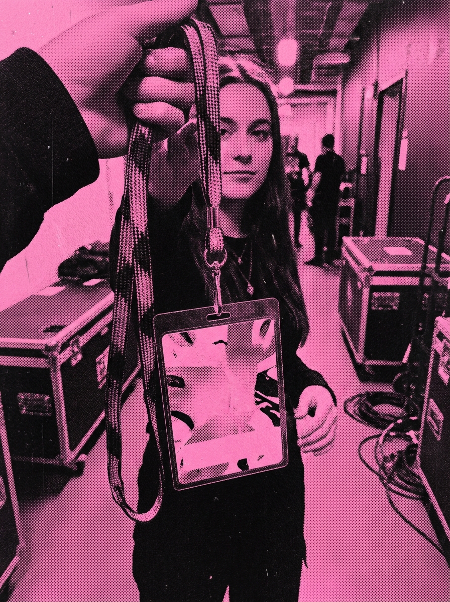 A backstage laminate held up in a venue corridor, duotone print